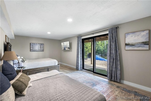 bedroom featuring a textured ceiling, access to exterior, and light hardwood / wood-style floors