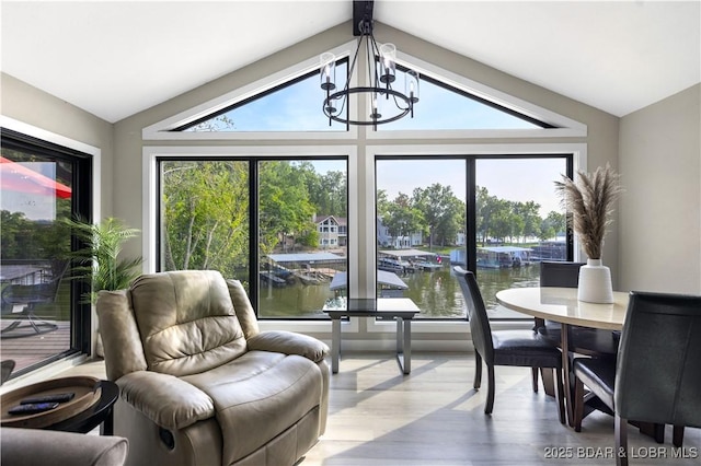 dining area featuring lofted ceiling, a chandelier, and a water view