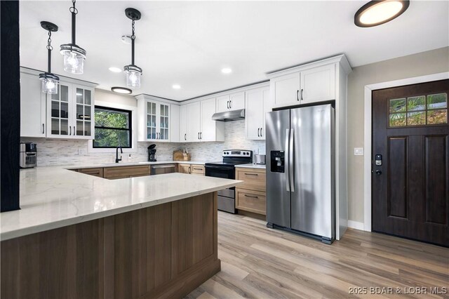 kitchen with light stone countertops, white cabinetry, pendant lighting, and appliances with stainless steel finishes