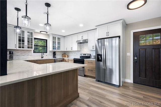 kitchen with pendant lighting, light stone countertops, white cabinetry, and stainless steel appliances