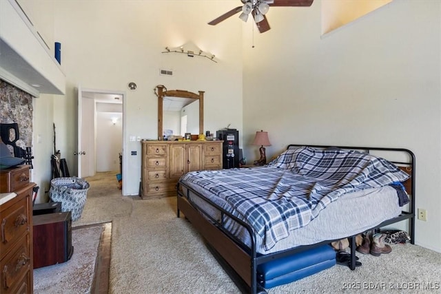 bedroom with a ceiling fan, a towering ceiling, visible vents, and light colored carpet