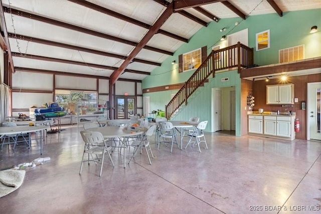 dining room featuring stairs, high vaulted ceiling, beam ceiling, and finished concrete floors