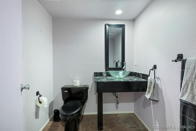 bathroom with a sink, toilet, and baseboards