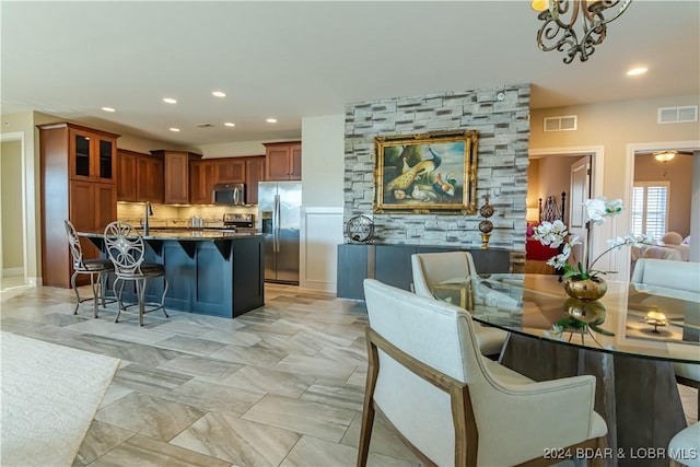 kitchen with a breakfast bar, backsplash, hanging light fixtures, dark stone countertops, and appliances with stainless steel finishes