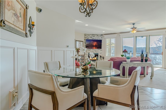 tiled dining space featuring a fireplace, a mountain view, and ceiling fan with notable chandelier