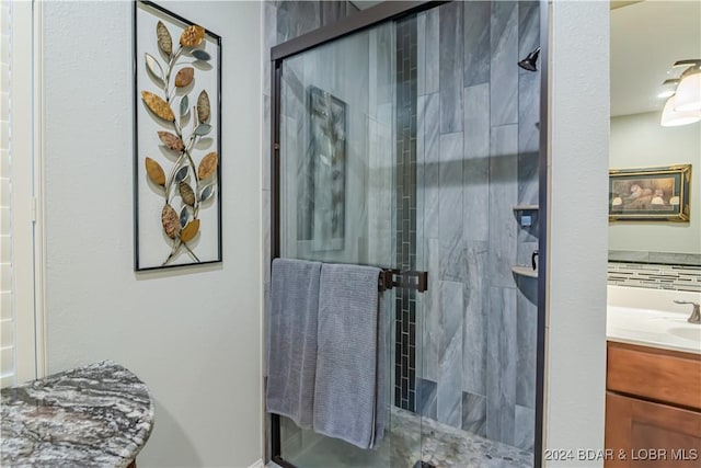 bathroom featuring a shower with door and vanity