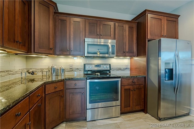 kitchen with decorative backsplash, appliances with stainless steel finishes, light tile patterned floors, and dark stone countertops