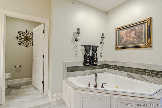 bathroom with a tub to relax in and toilet