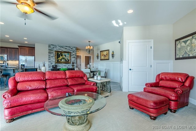 living room with ceiling fan with notable chandelier and light colored carpet