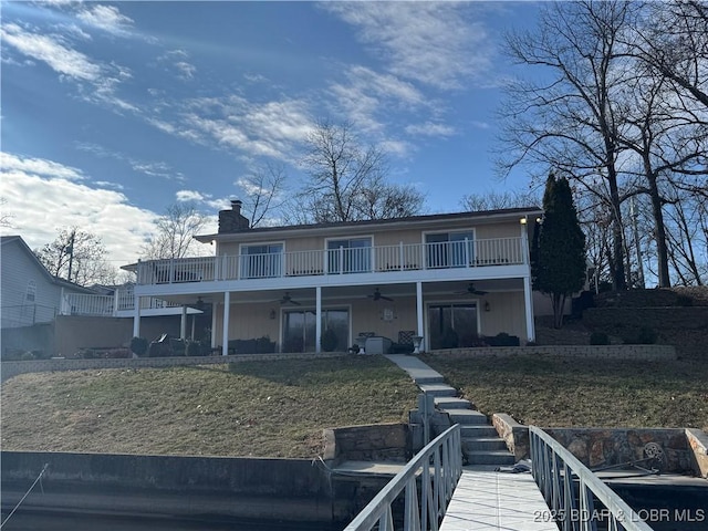 view of front facade featuring a ceiling fan, a chimney, and a front lawn