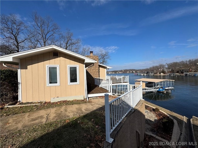 view of property exterior with a water view, a floating dock, and a chimney