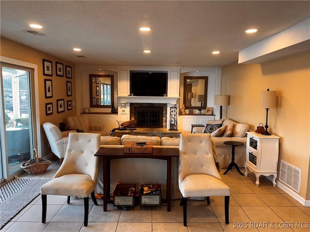 living room with recessed lighting, visible vents, a textured ceiling, and a glass covered fireplace