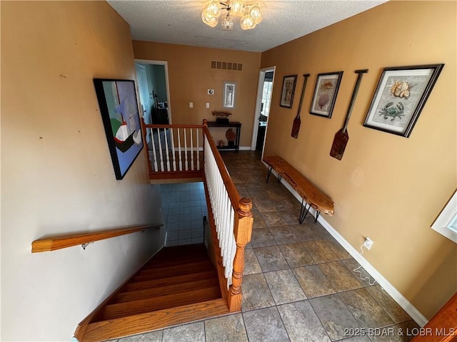 staircase with a textured ceiling, visible vents, and baseboards