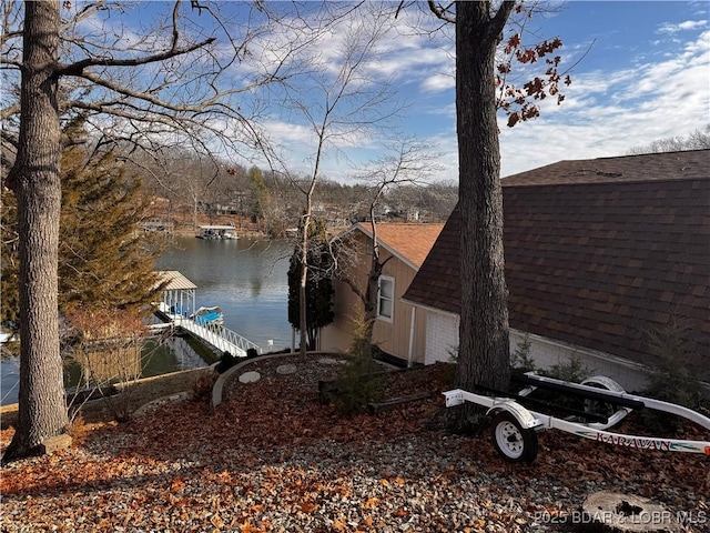 exterior space featuring a water view, a floating dock, a garage, and roof with shingles