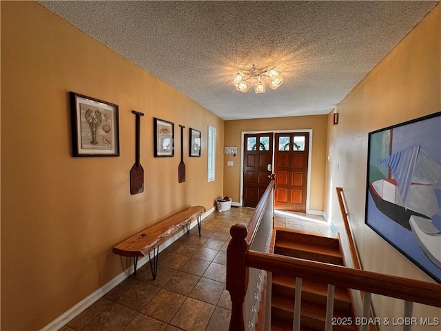 entrance foyer featuring dark tile patterned floors, baseboards, and a textured ceiling