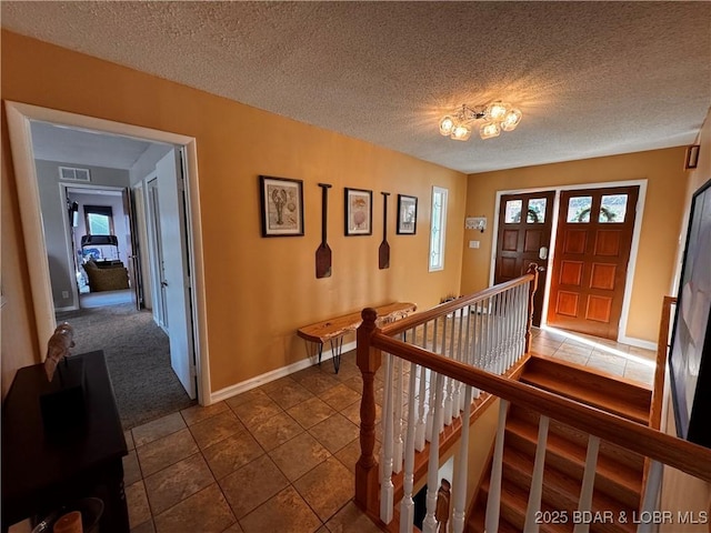 tiled foyer entrance featuring a textured ceiling, plenty of natural light, visible vents, and baseboards