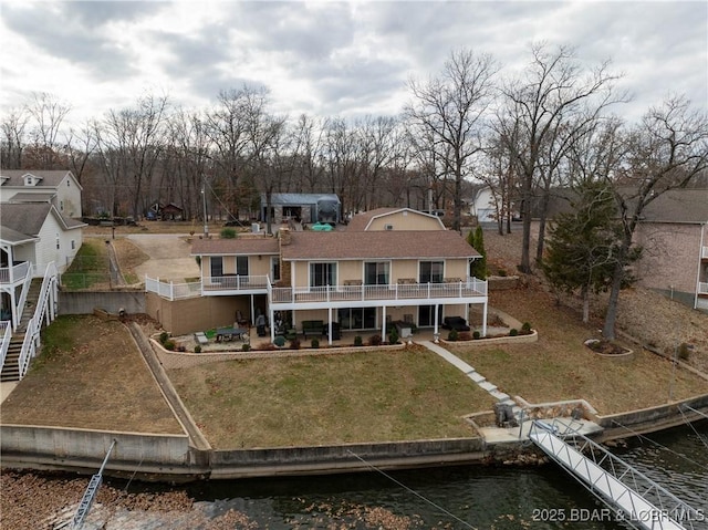 back of property with a yard, a patio area, a balcony, and a water view