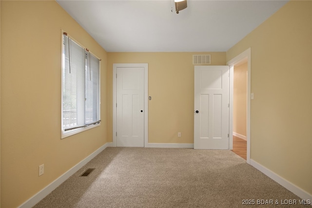 unfurnished bedroom with ceiling fan and light colored carpet