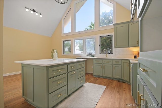 kitchen featuring decorative backsplash, light wood-type flooring, high vaulted ceiling, a center island, and green cabinets