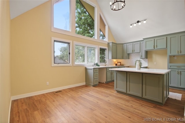 kitchen with an inviting chandelier, light hardwood / wood-style flooring, high vaulted ceiling, decorative backsplash, and a kitchen island