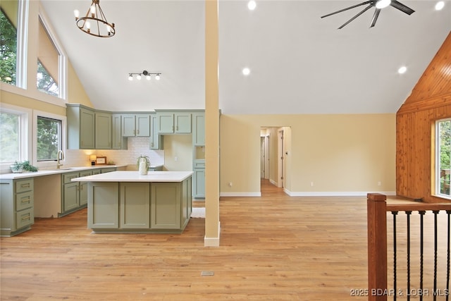 kitchen featuring ceiling fan with notable chandelier, backsplash, light hardwood / wood-style flooring, and green cabinets