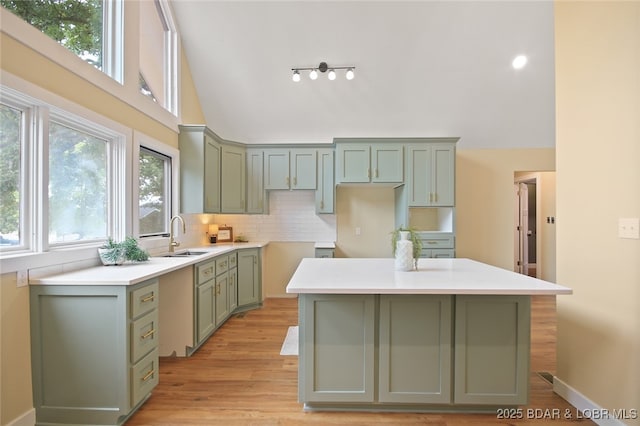 kitchen featuring tasteful backsplash, sink, a center island, light hardwood / wood-style floors, and green cabinets