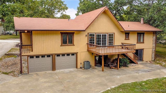 rear view of house with cooling unit, a garage, and a deck