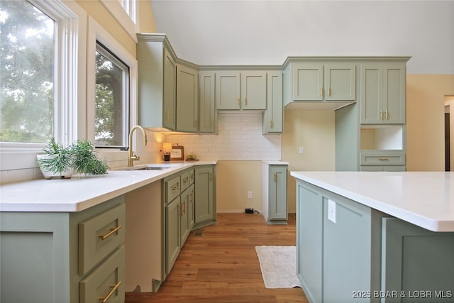 kitchen with backsplash, green cabinets, sink, and light hardwood / wood-style floors