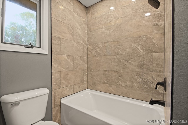 bathroom with tiled shower / bath combo and toilet