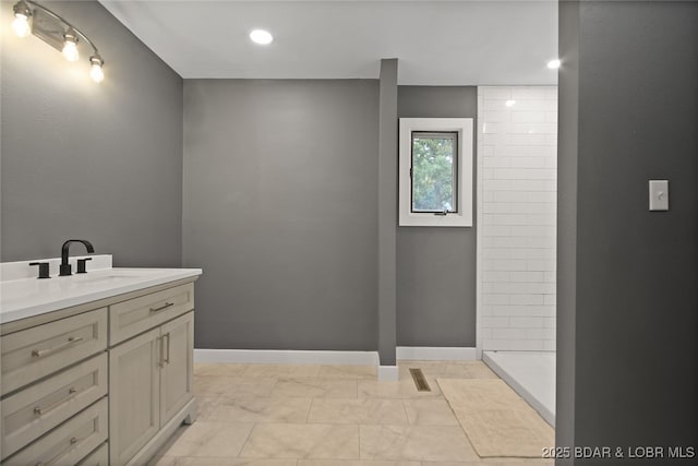 bathroom with a tile shower and vanity