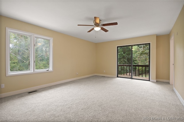 carpeted spare room featuring a wealth of natural light and ceiling fan