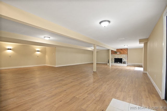 basement with a fireplace and light hardwood / wood-style flooring