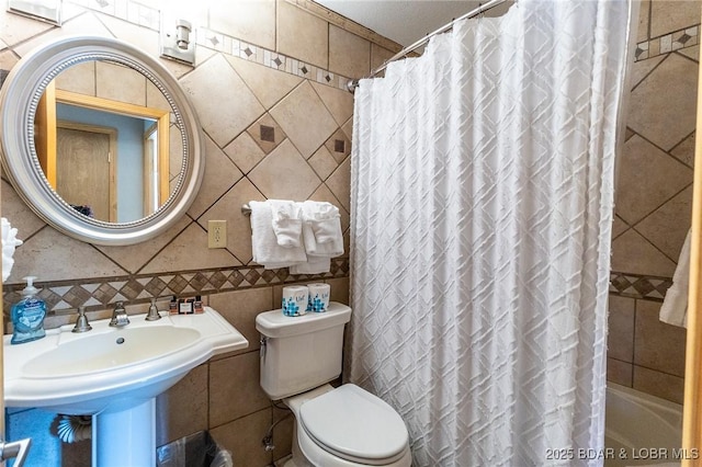 bathroom featuring toilet and tile walls