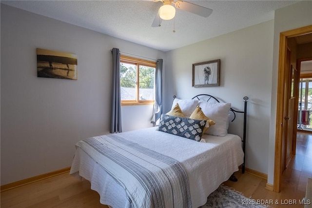 bedroom featuring ceiling fan, light wood-type flooring, and a textured ceiling