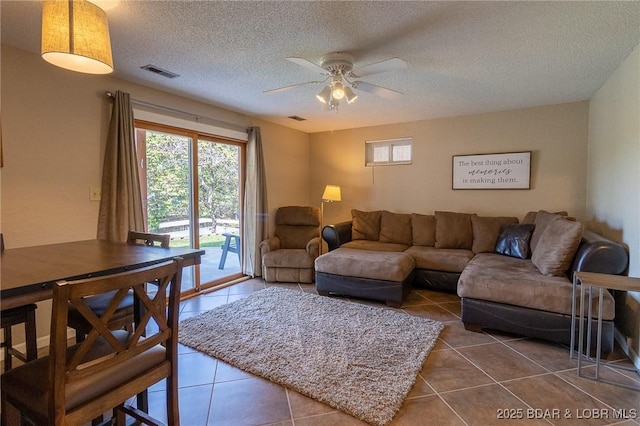 living room featuring ceiling fan, tile patterned flooring, and a textured ceiling