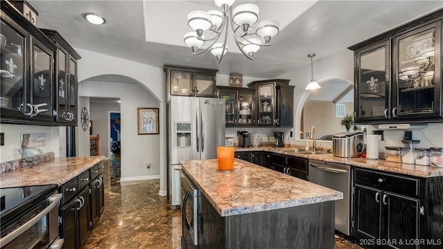 kitchen featuring appliances with stainless steel finishes, sink, decorative light fixtures, a chandelier, and a center island