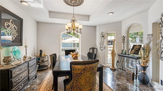 dining area with a chandelier and a raised ceiling