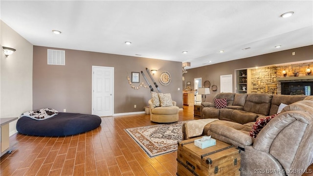 living room with hardwood / wood-style floors, a stone fireplace, and built in features