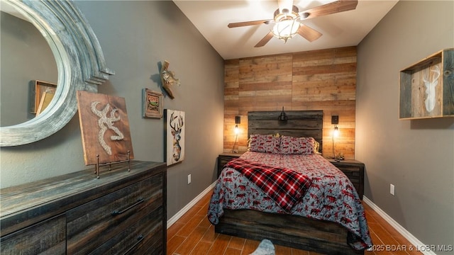 bedroom featuring ceiling fan and wood walls