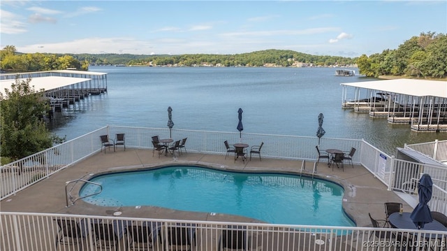 view of swimming pool featuring a water view, a boat dock, and a patio area