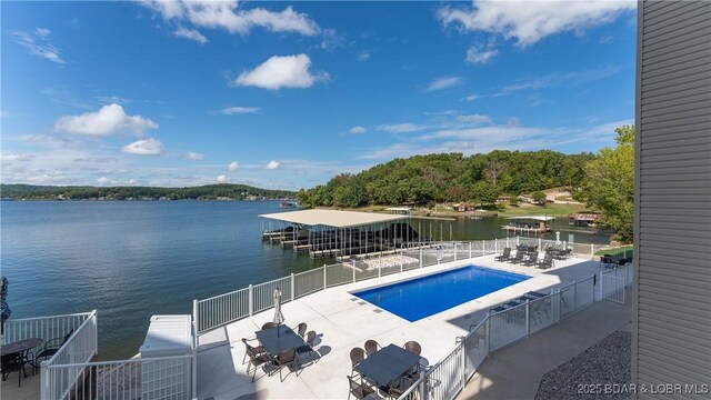 view of pool featuring a patio, a boat dock, and a water view