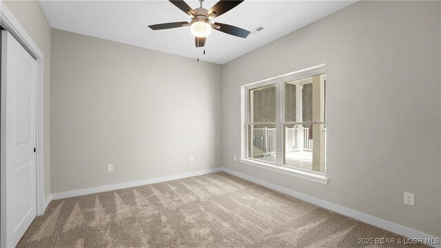 carpeted spare room featuring plenty of natural light and ceiling fan