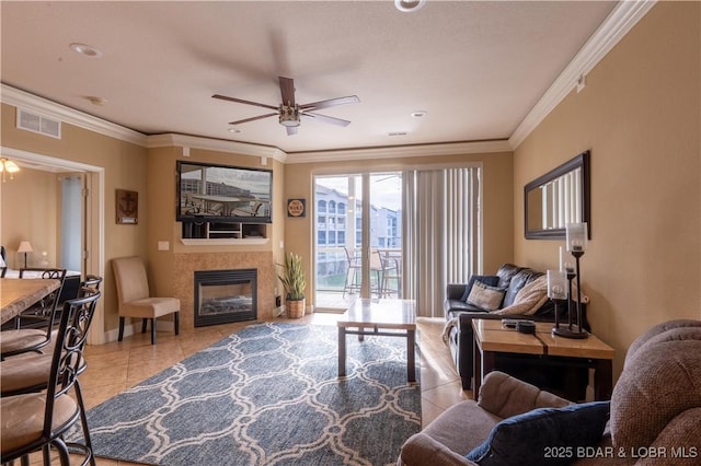 tiled living room featuring a tile fireplace, ceiling fan, and crown molding