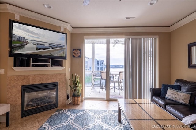 living room with a tiled fireplace, crown molding, and light tile patterned floors