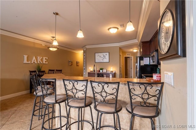 kitchen with a kitchen breakfast bar, light tile patterned floors, hanging light fixtures, and ornamental molding