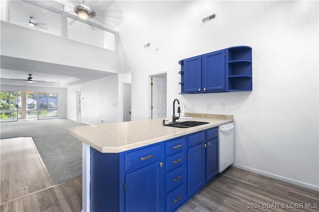 kitchen featuring blue cabinetry, sink, white dishwasher, kitchen peninsula, and a towering ceiling