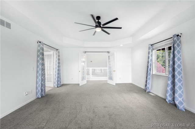 carpeted empty room featuring ceiling fan and a raised ceiling