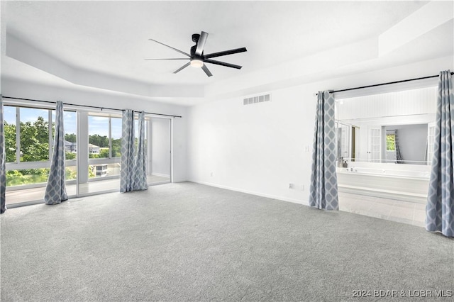 spare room featuring a tray ceiling, ceiling fan, and carpet flooring