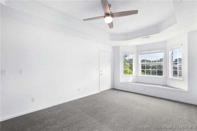 empty room featuring carpet, a textured ceiling, ceiling fan, and a tray ceiling