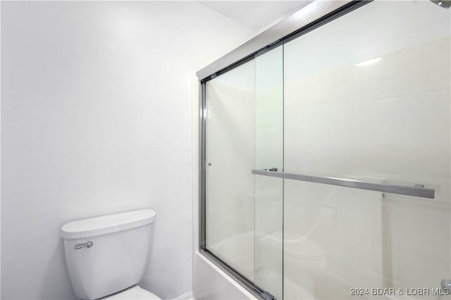 bathroom with bath / shower combo with glass door and toilet